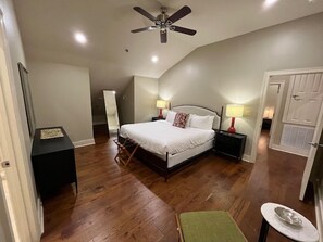 A bedroom with a bed, bedside tables, a ceiling fan, and a door. - Comfortable 2BR New Orleans vacation rental in Bywater, sleeping 4 with 2 queen beds. Located at historic Burgundy & Piety, steps from Crescent Park and a short ride to Frenchmen Street & the French Quarter. (New Orleans)