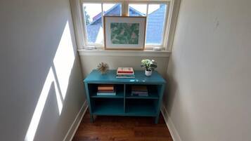 A corner room with a window, a teal bookshelf, and a small plant.