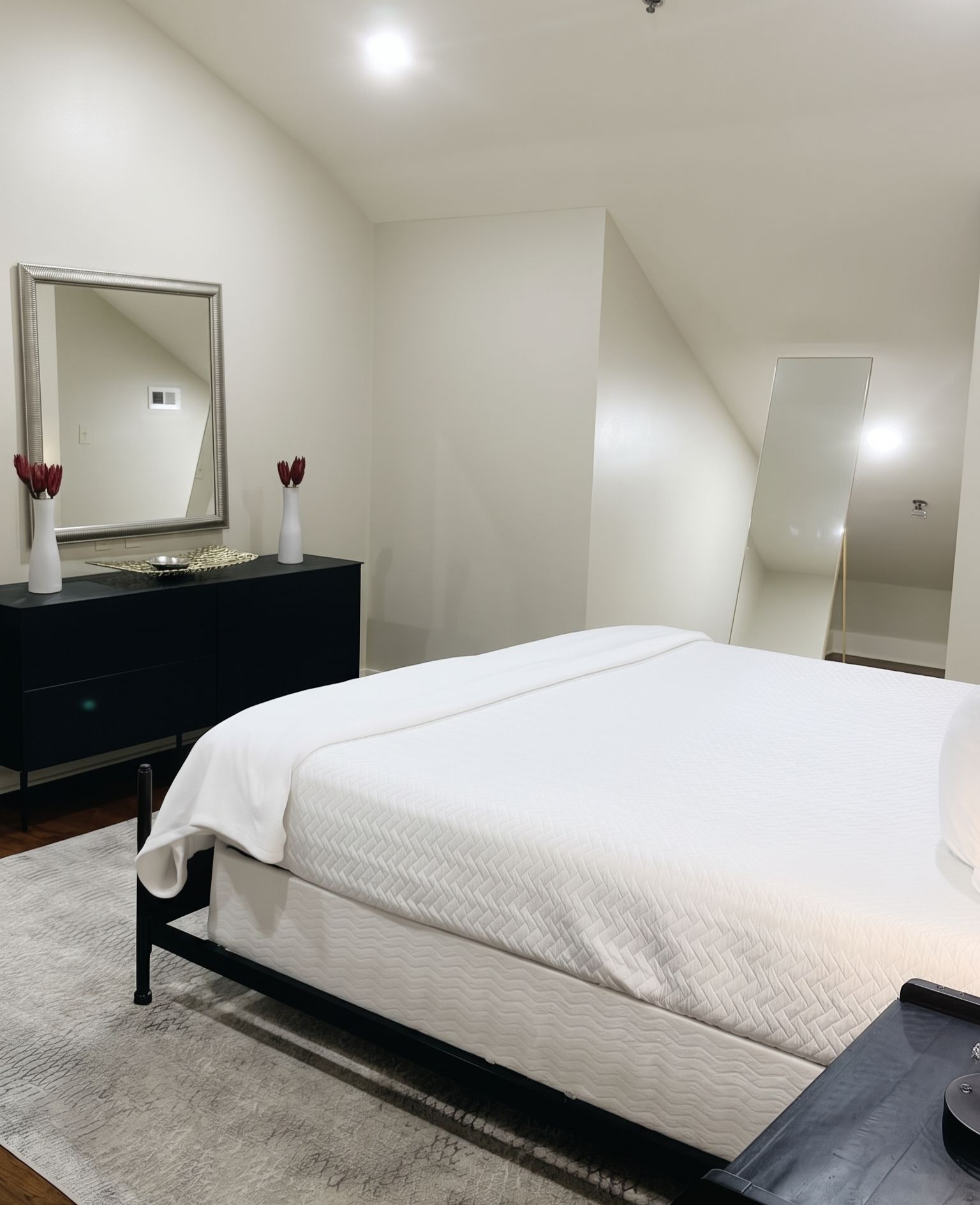 Ein Schlafzimmer mit einem Bett, einem Schminktisch, einem Spiegel und einem modernen Deckenstil.