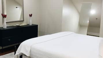 Ein Schlafzimmer mit einem Bett, einem Schminktisch, einem Spiegel und einem modernen Deckenstil.