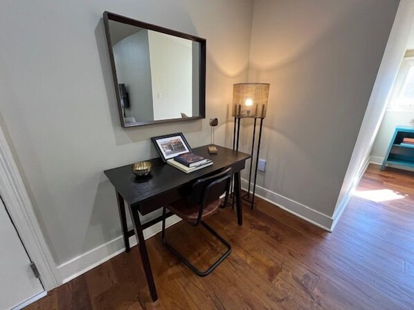 A room with a desk, a chair, a lamp, and a mirror on the wall. - Comfortable 2BR New Orleans vacation rental in Bywater, sleeping 4 with 2 queen beds. Located at historic Burgundy & Piety, steps from Crescent Park and a short ride to Frenchmen Street & the French Quarter. (New Orleans)