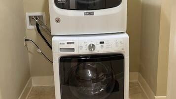 A stacked washer and dryer unit in a corner with a visible power outlet.