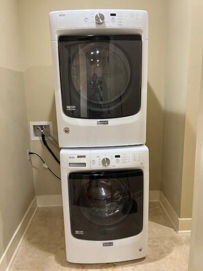 A stacked washer and dryer unit in a corner with a visible power outlet. - Comfortable 2BR New Orleans vacation rental in Bywater, sleeping 4 with 2 queen beds. Located at historic Burgundy & Piety, steps from Crescent Park and a short ride to Frenchmen Street & the French Quarter. (New Orleans)