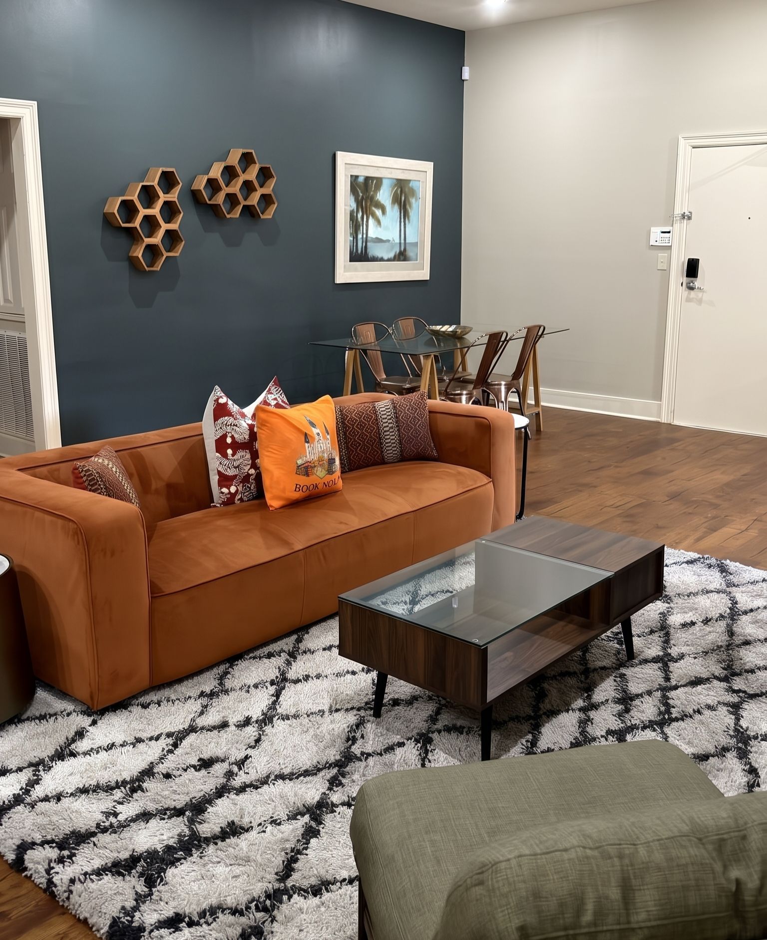 A living room with a brown sofa, a glass coffee table, and a patterned rug.