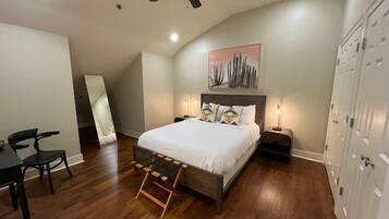 A bedroom with a bed, bedside tables, a ceiling fan, a large mirror, and a wardrobe.