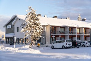 Ein Hotel mit einem zweigeschossigen Gebäude, einem überdachten Außenbereich und einem Parkplatz mit mehreren Autos.