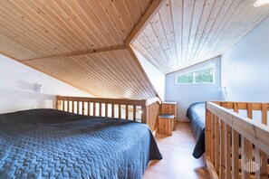 A bedroom with a sloped ceiling, wooden bunk beds, a window, and a small bedside table. - Postintie 1608 by Holiday in Lapland (Levi)