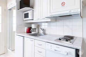 A modern kitchen with white cabinetry, a microwave, a coffee maker, and a gas stove. - Postintie 1608 by Holiday in Lapland (Levi)