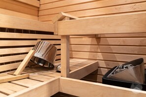 Un sauna avec des bancs en bois et un récipient en métal pour les cendres.