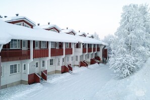 A multi-story hotel with balconies, snow-covered surroundings, and a clear sky. - Postintie 1509 by Holiday in Lapland (Levi)
