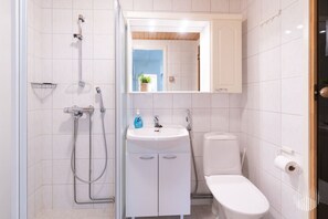 Ein modernes Badezimmer mit Dusche, Waschbecken, Toilette und einem Spiegel über dem Waschbecken.
