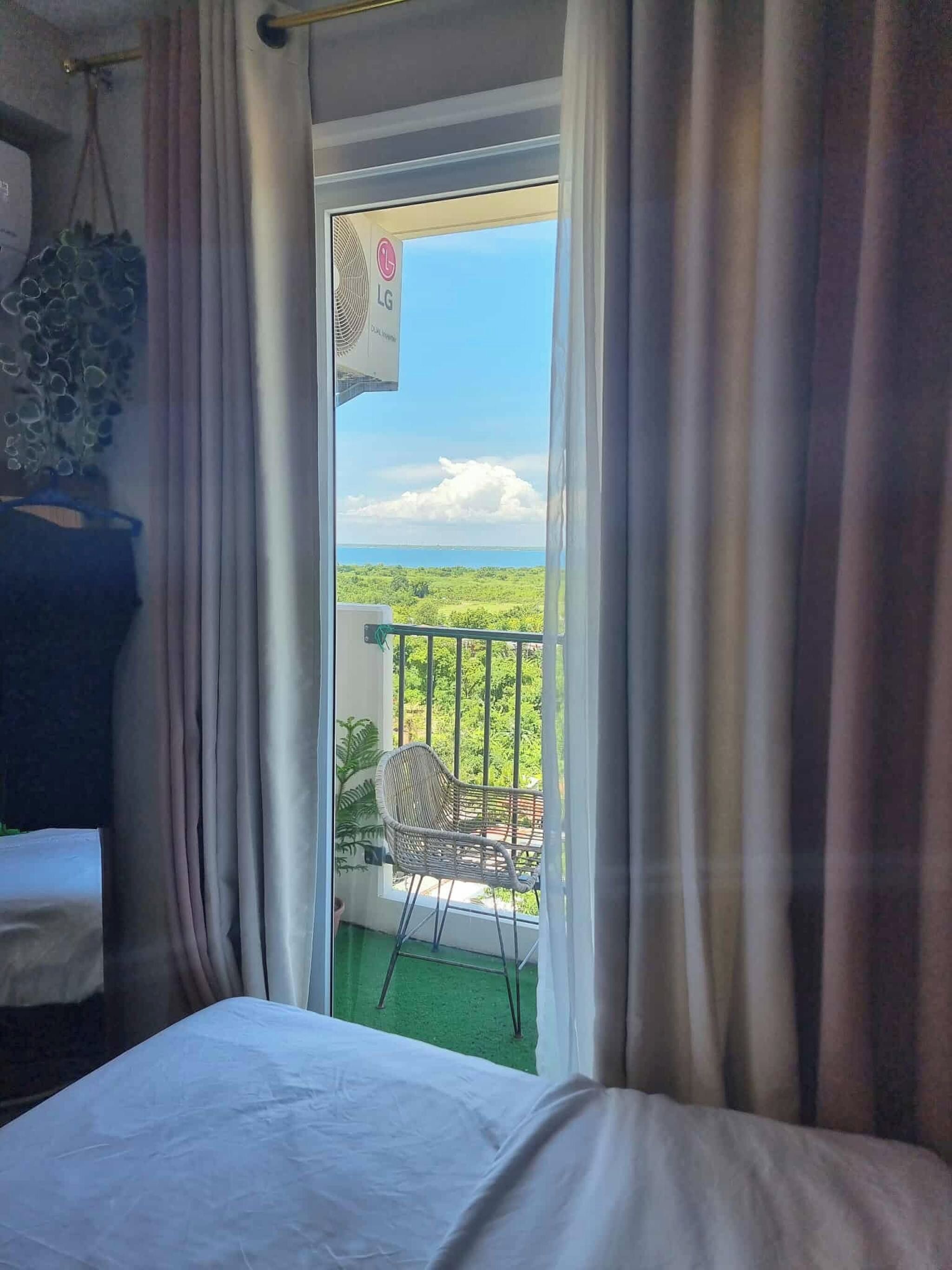 Quarto de hotel com uma cama, uma cadeira e varanda com vista para o mar.