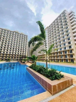 A swimming pool surrounded by high-rise residential buildings. - Oceanview Escape Steps to Shore Private Balcony (Lapu-Lapu)