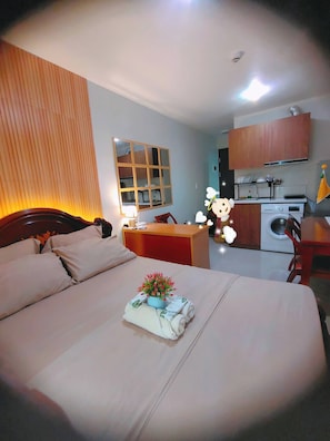 A hotel room with a bed, a desk, a small kitchen area, and a bathroom. - Oceanview Escape Steps to Shore Private Balcony (Lapu-Lapu)