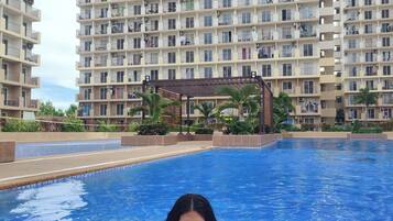 A swimming pool with tiled flooring, surrounded by high-rise residential buildings.
