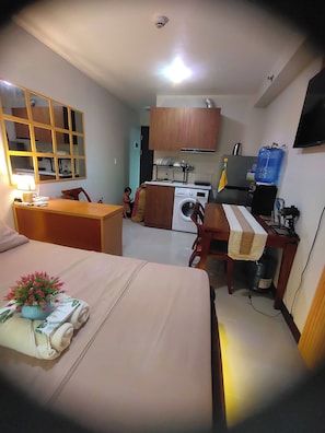 A compact hotel room with a bed, a desk, a washing machine, and a kitchenette. - Oceanview Escape Steps to Shore Private Balcony (Lapu-Lapu)