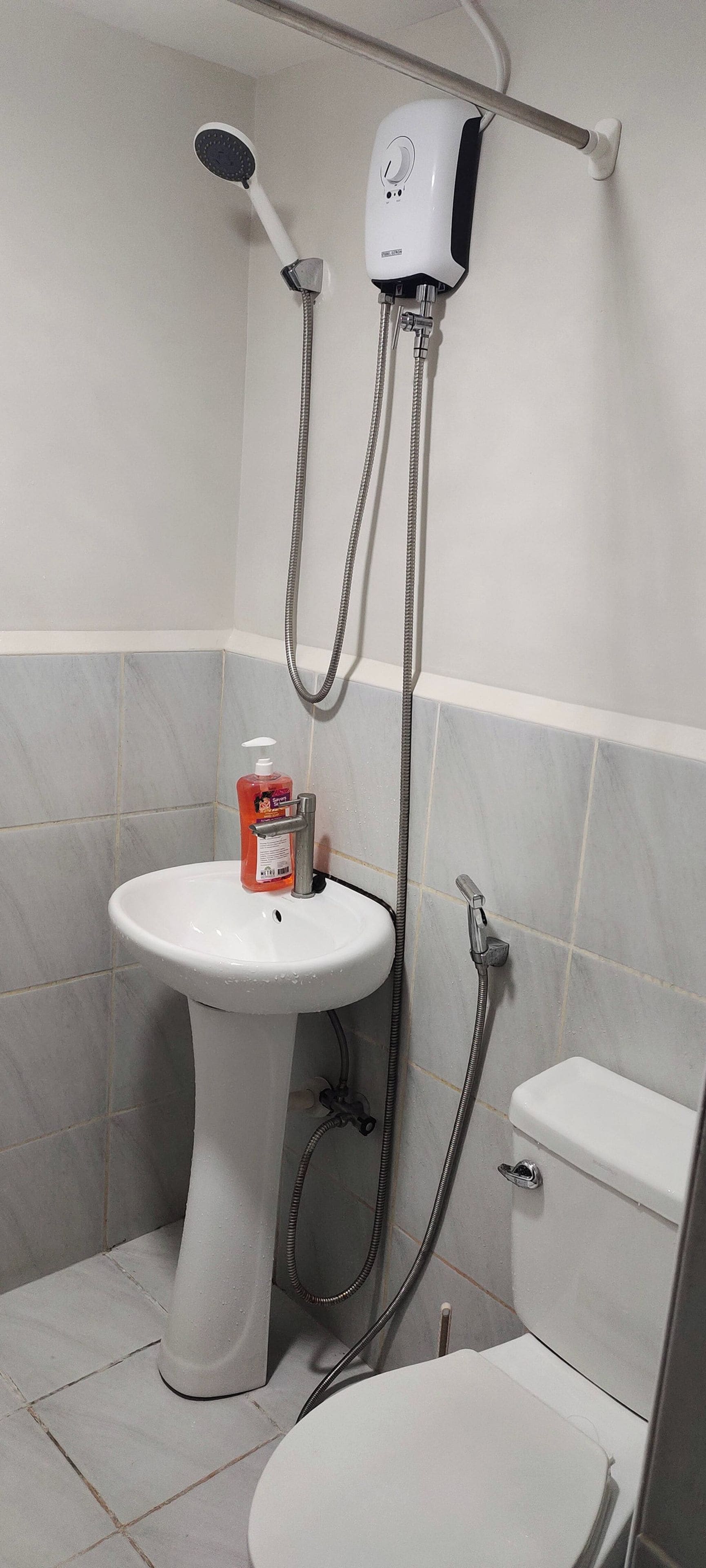 Une salle de bain équipée d’un lavabo sur colonne, de toilettes et d’une douche.
