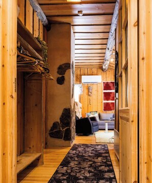 A wooden interior with a stone wall, a sofa, and a patterned rug. - Villa Pönttölä by Holiday in Lapland (Ruka)