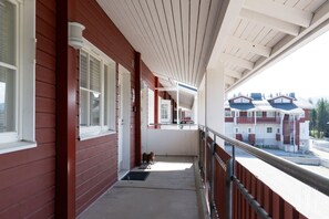 A covered balcony with a view of a building with red and white exterior. - Postintie 1617 by Holiday in Lapland (Levi)