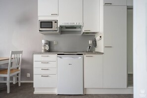 Eine kompakte Küche mit Mikrowelle, Kaffeemaschine und Geschirrspüler.
