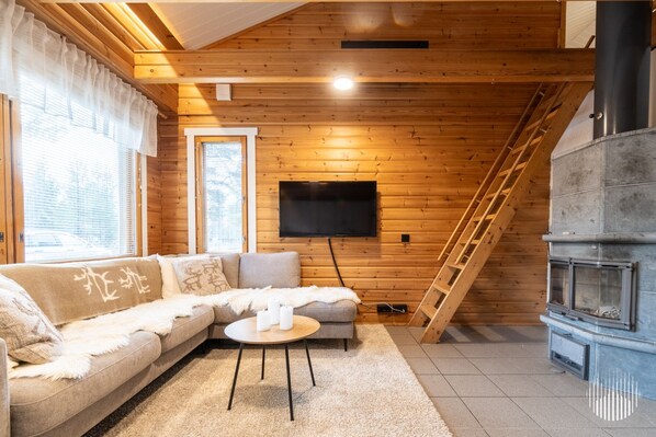 Un salon chaleureux avec un plafond en bois, un canapé, une table basse, une cheminée et un téléviseur fixé au mur.