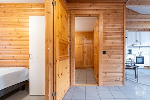 Un intérieur en bois comprenant un lit, un coin cuisine et un couloir.