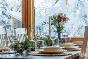 Une table à manger dressée pour un repas, avec de la vaisselle transparente, des assiettes et un chandelier en guise de décoration centrale.