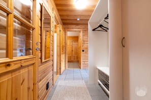 Un couloir en bois avec un sol carrelé, un porte-manteau et une cheminée.