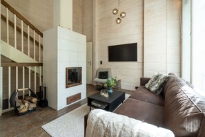 Un salon avec une cheminée, un canapé, une table basse et un téléviseur fixé au mur.