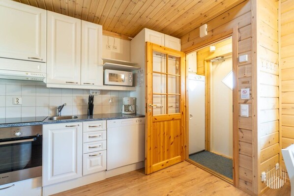 A compact kitchen with white cabinets, a microwave, a coffee maker, and a Bosch oven.
