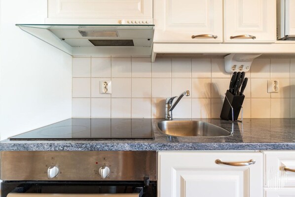 A kitchen with a stainless steel sink, a range hood, and a knife block.