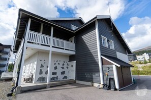 A two-story building with a balcony, a garage, and a driveway.