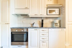 A kitchen with white cabinets, a Bosch oven, a microwave, and a coffee maker.
