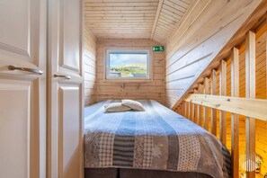 A narrow room with a bed, a window, and a door.