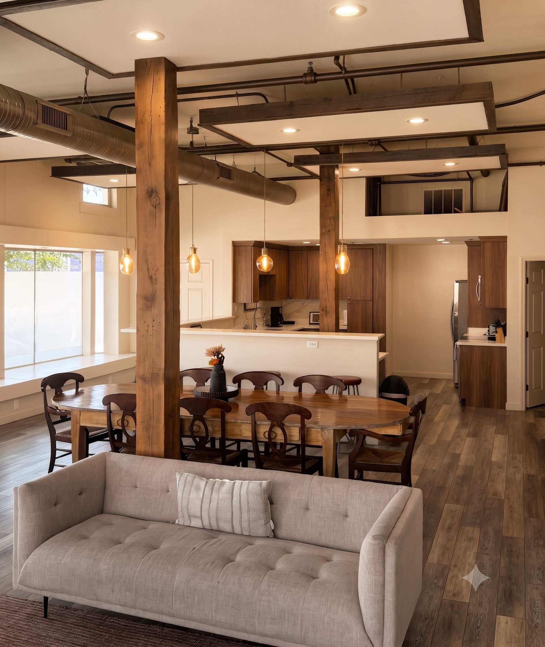 A modern kitchen with wooden cabinets, a dining area with a round table and chairs, and a living room with a sofa.