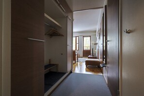 A hallway leading to a bedroom with a bed, a desk, and a chair.