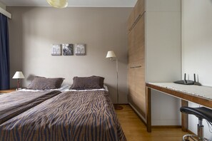 Quarto com cama, luminárias de cabeceira, escrivaninha e guarda-roupa.