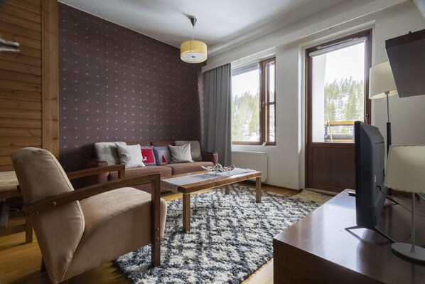 A modern living room with a sofa, armchairs, a coffee table, and a television.