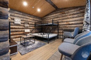 L’intérieur d’une cabane en rondins, avec un lit superposé, un bureau, une chaise et un canapé.