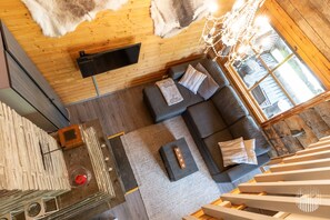 Un intérieur moderne avec un plafond en bois, un ensemble de canapés, un lustre et une vue par la fenêtre.