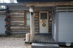 A log cabin with a front door labeled 'Hilleville,' a porch with a lamp post, and a wreath on the door.