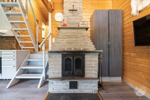 A modern interior with a stone fireplace, wooden walls, a white staircase, and a grey wardrobe.