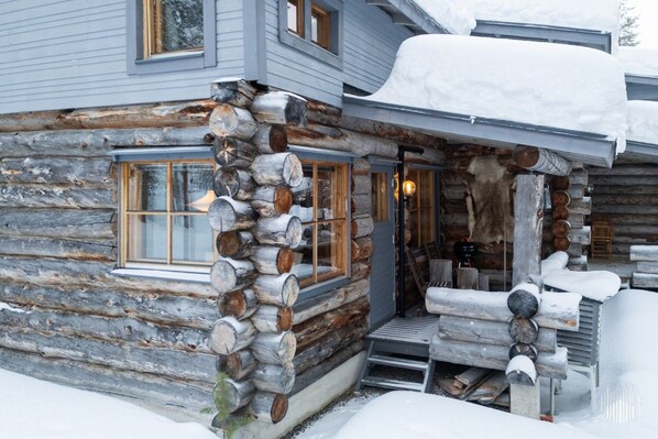 A log cabin with a porch, a fireplace, and a window.