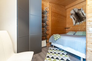A bedroom with a bed, a chair, a rug, and a fur rug on the wall.