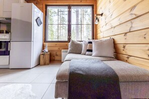 Ein gemütliches Zimmer mit einem Bett, einem kleinen Tisch, einem weißen Gerät und einem Fenster mit Blick auf Bäume.