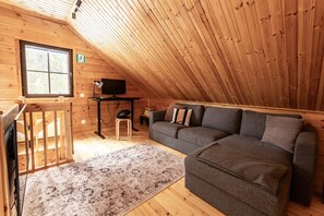 Un accogliente chalet con interni in legno, un divano, un tavolino e un televisore.