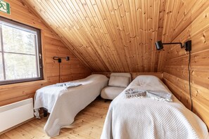 Una camera accogliente con due letti, una finestra e un soffitto in legno.