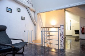 A room with a chair, a radiator, a ladder, and a door leading to another space. - Penthouse apartment—15 minutes from Europa-Park (Kenzingen)