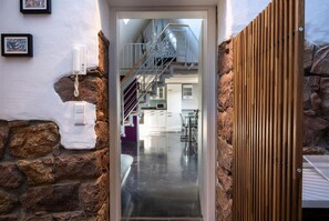A modern interior with a staircase leading to a second floor, a kitchen area, and a stone wall. - Penthouse apartment—15 minutes from Europa-Park (Kenzingen)