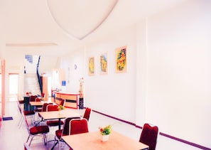 A hotel room with a dining area, a staircase, and artwork on the walls.